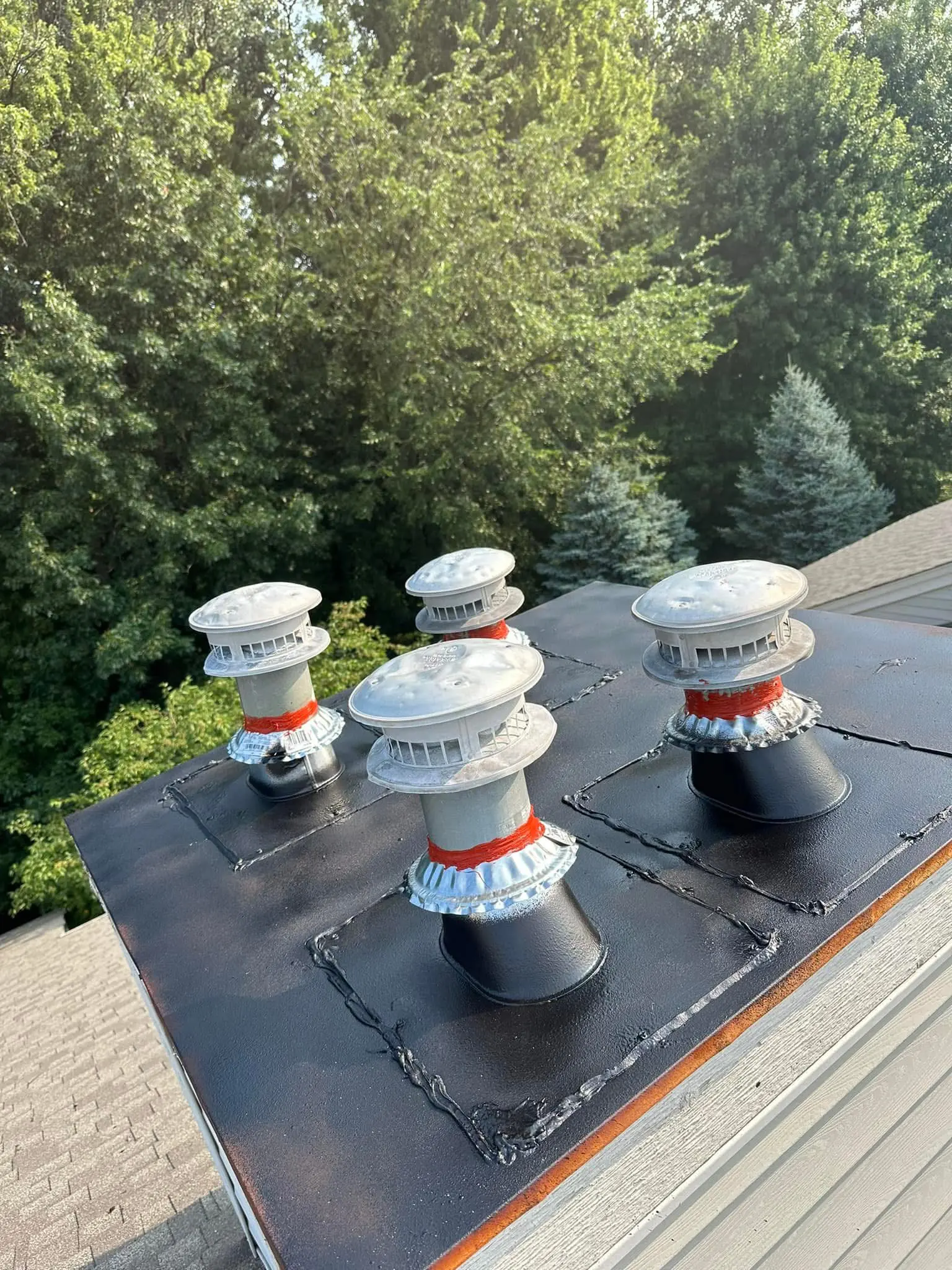 Four metal roof vents with black flashing