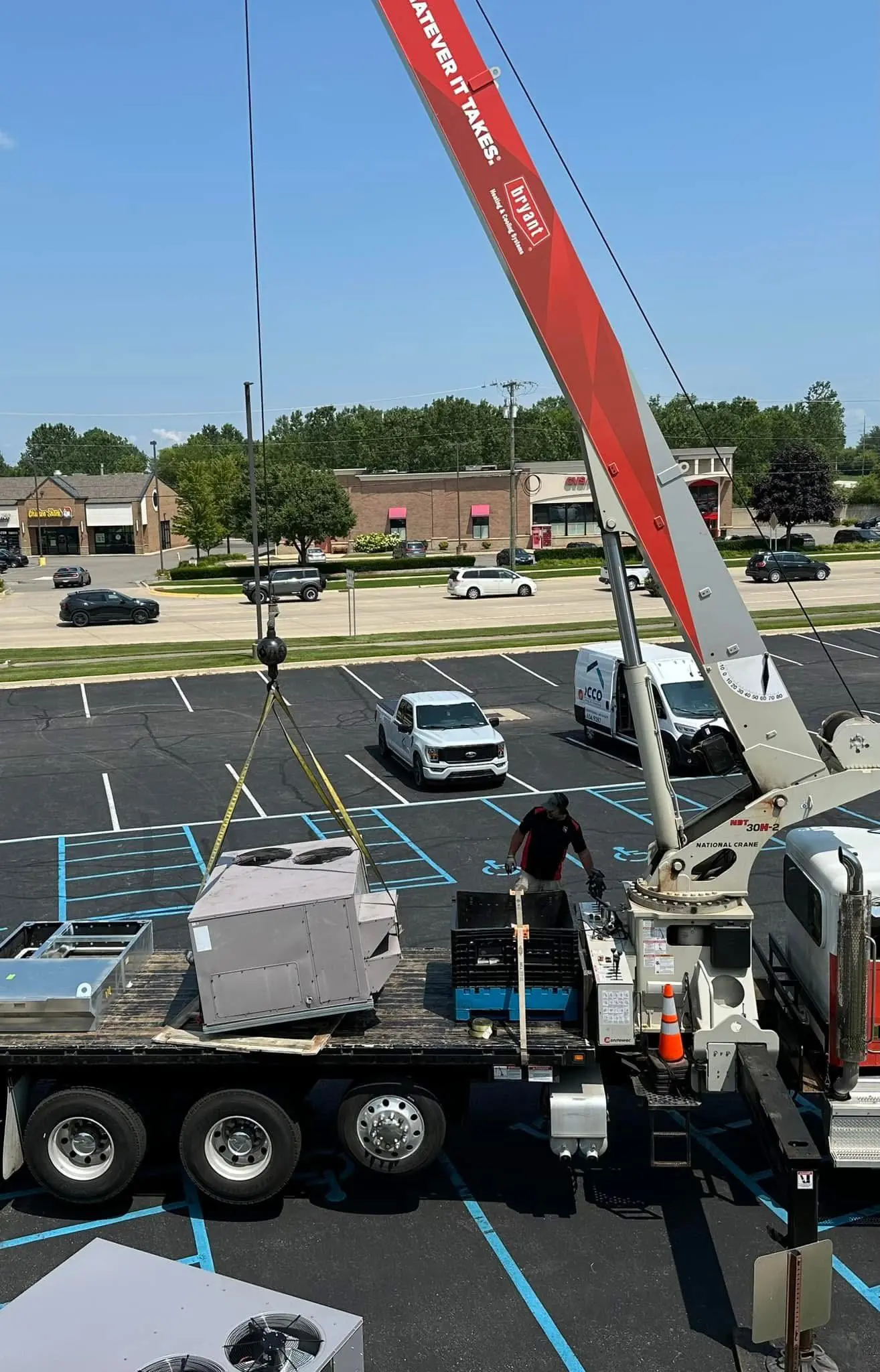 Crane lifting HVAC units from flatbed truck