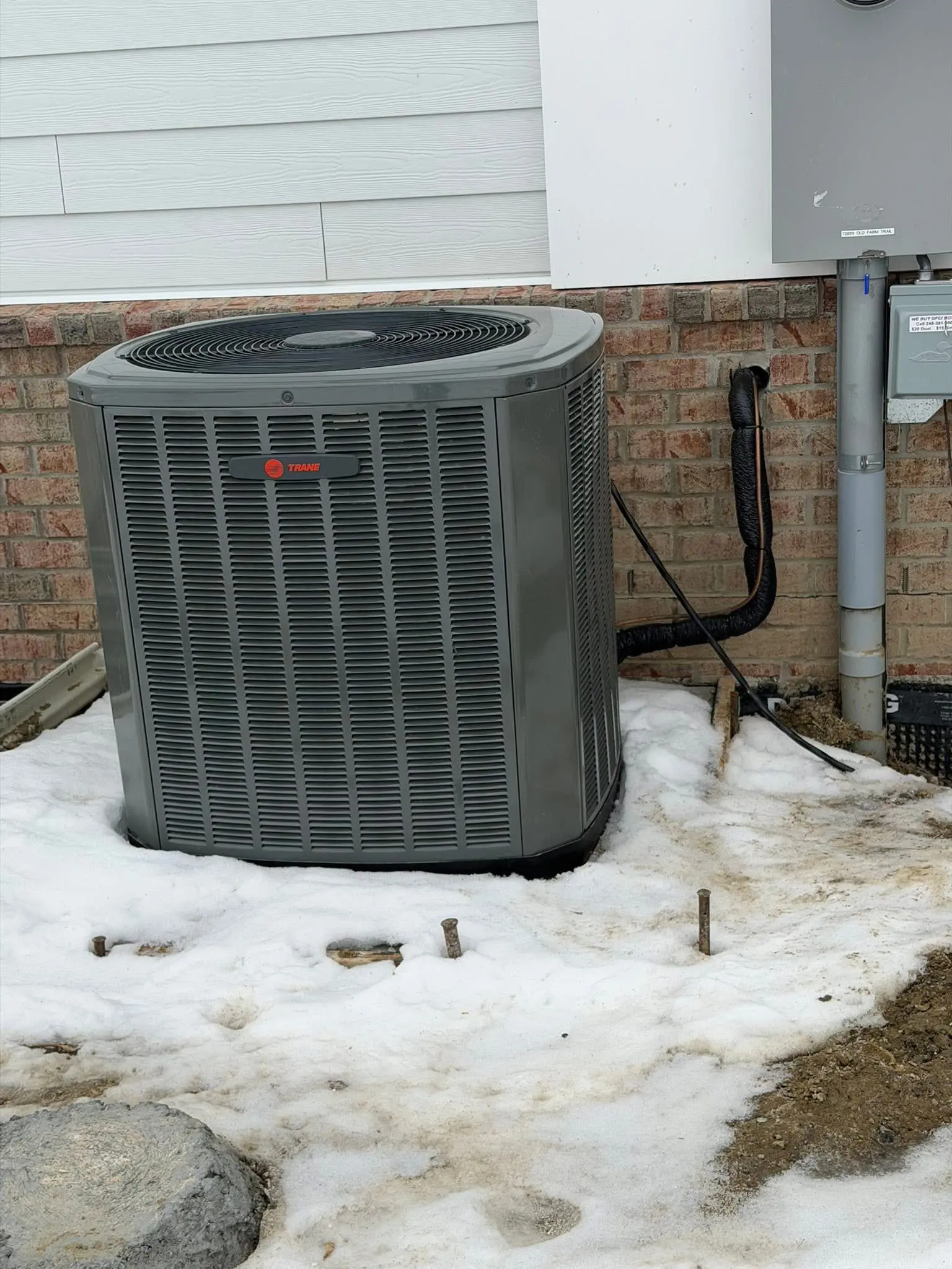 Gray Trane outdoor AC unit on snow