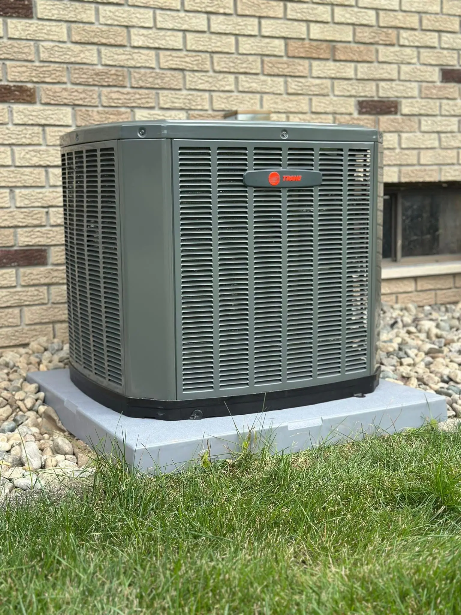 Outdoor air conditioning unit beside brick house