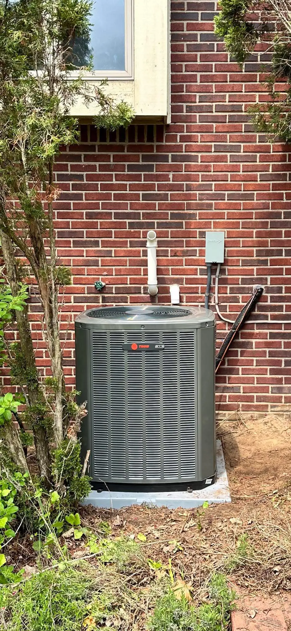 Outdoor air conditioning unit beside brick wall